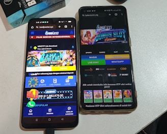Two smartphones are displayed on a white surface, both showing gambling websites with colorful graphics, text, and various options for logging in and accessing games. The screens are bright and filled with promotional content related to casino and slot games.